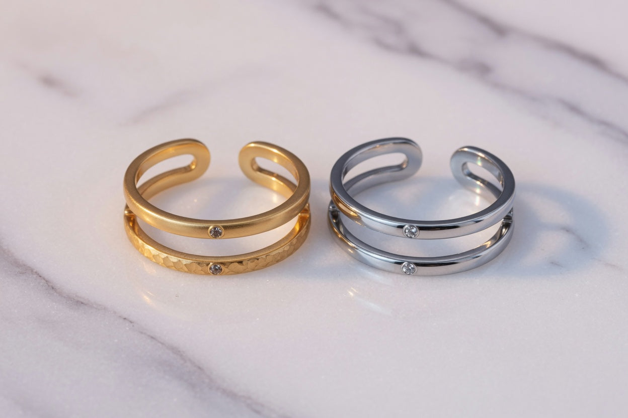 Gold PVD and stainless steel toe rings side by side on marble