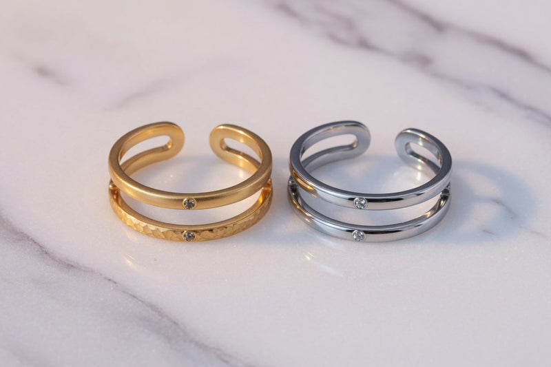 Gold PVD and stainless steel toe rings side by side on marble